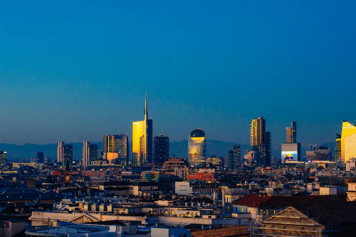 Nowoczesna panorama Mediolanu o zachodzie słońca z wyraźnymi drapaczami chmur, odzwierciedlająca zarówno potęgę finansową, jak i design w tętniącym życiem krajobrazie miejskim.