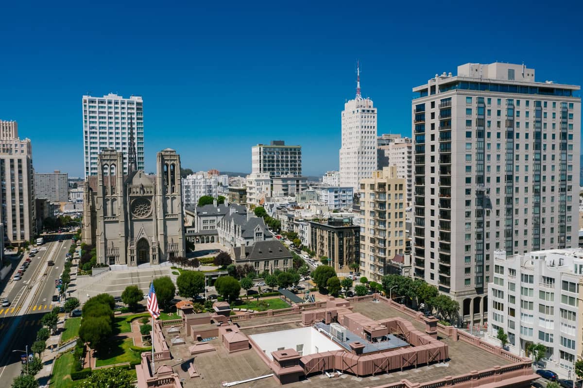 Vista aerea di Nob Hill a San Francisco con hotel di lusso, la Grace Cathedral e prominenti grattacieli sotto un cielo azzurro limpido.