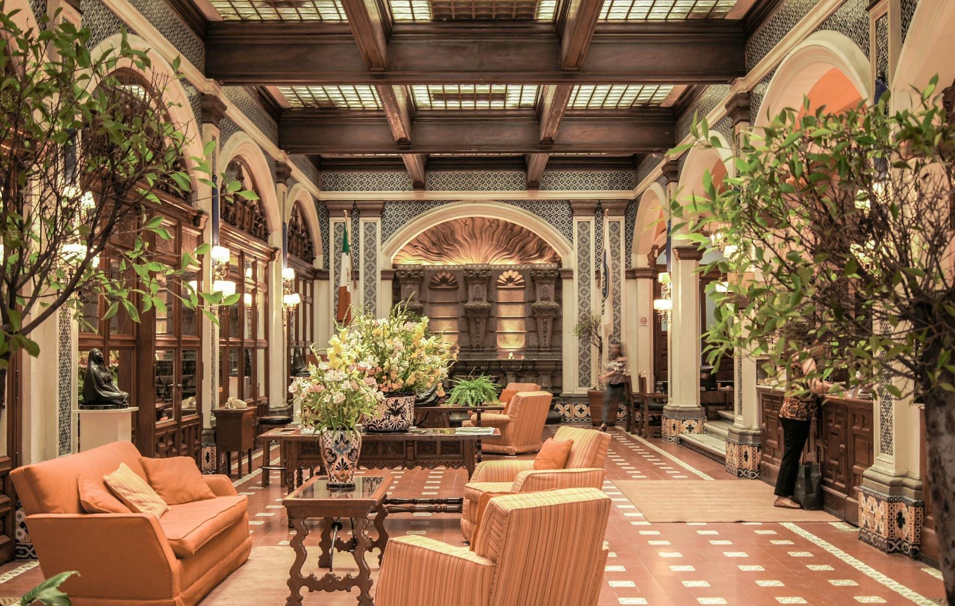 Elegante Hotellobby mit plüschigen Sesseln, großen Blumenarrangements, Bogentüren und einer kunstvollen Decke im traditionellen sizilianischen Stil.