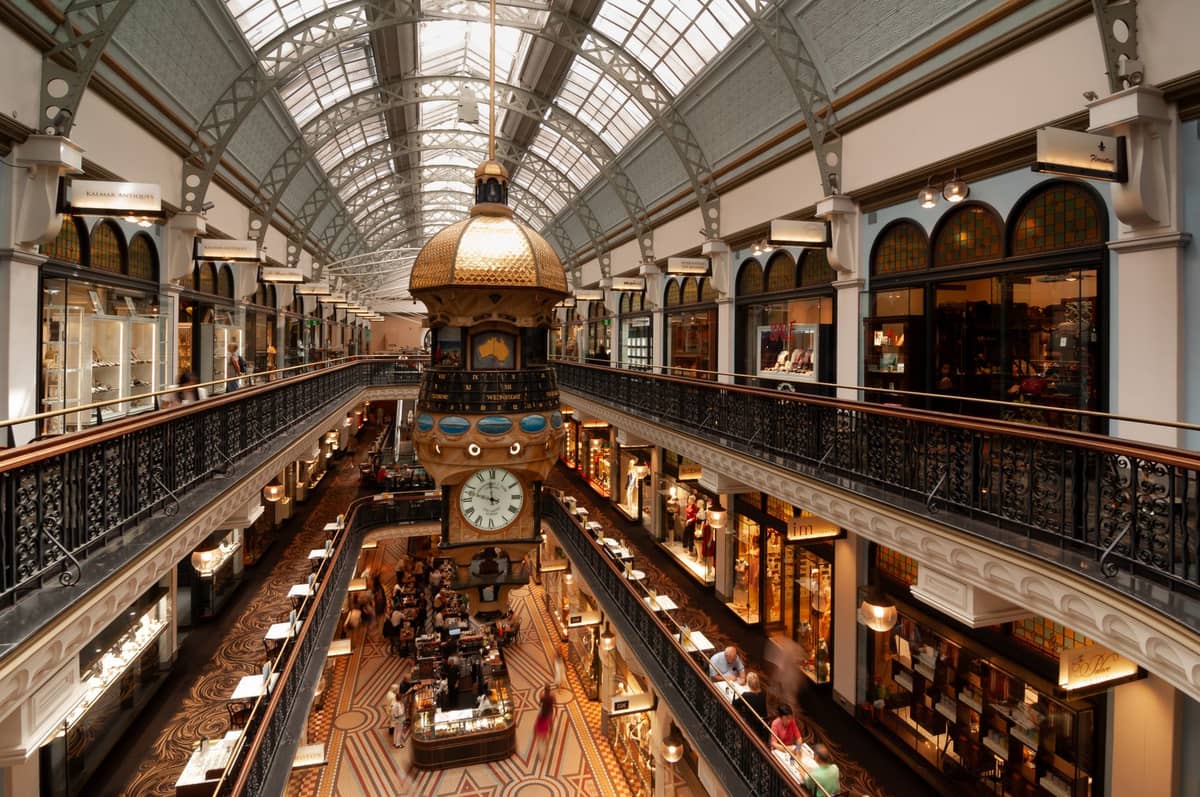Interior view of Sydney's Queen Victoria Building with luxury shops, ornate details, glass roof, and central clock tower.