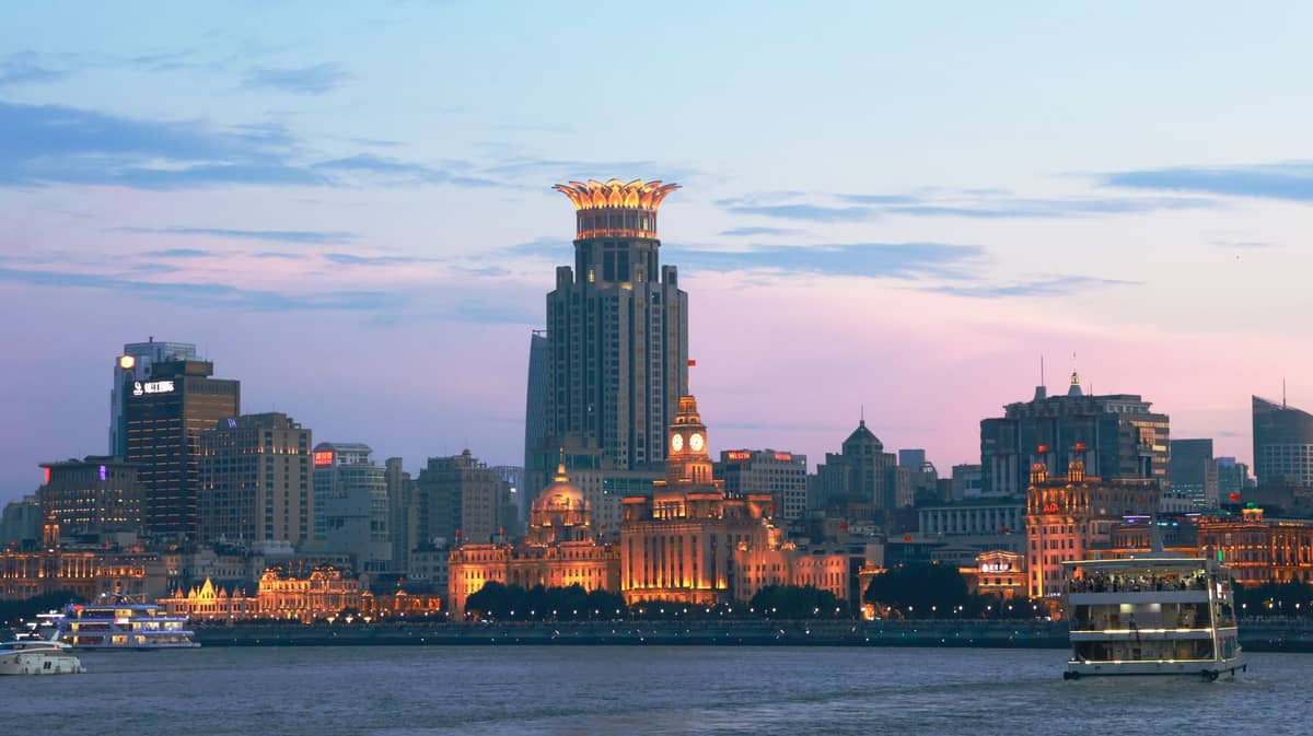Weitwinkelansicht des Bund in Shanghai bei Sonnenuntergang mit historischen Ufergebäuden und Luxushotels mit Blick auf den Huangpu.