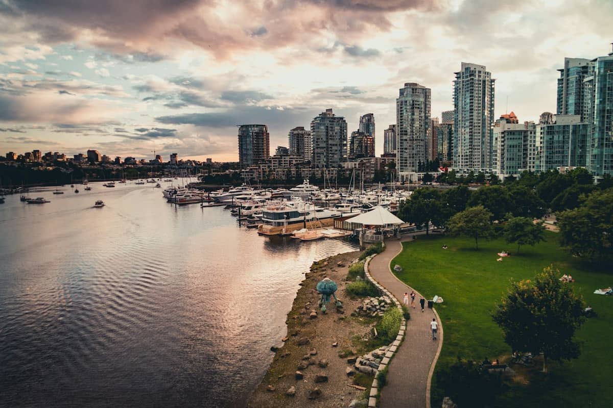 วิวริมน้ำของ Vancouver พร้อมเรือยอชต์หรูจอดเทียบท่าที่มาริน่า อาคารสูงทันสมัย และเส้นทางเดินชมวิวที่สวยงามยามพระอาทิตย์ตกดิน