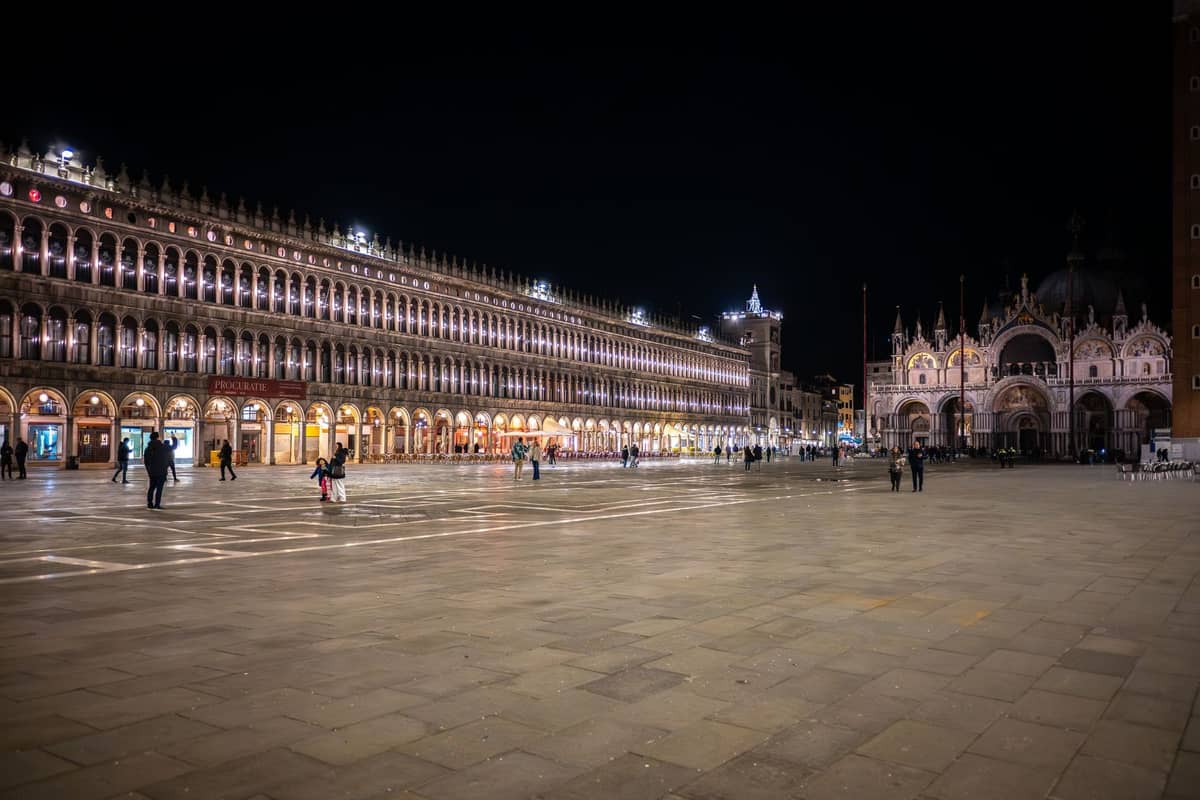 Der Markusplatz in Venedig bei Nacht mit dem Markusdom und den umliegenden Gebäuden elegant beleuchtet, nur sehr wenige Menschen sind anwesend.