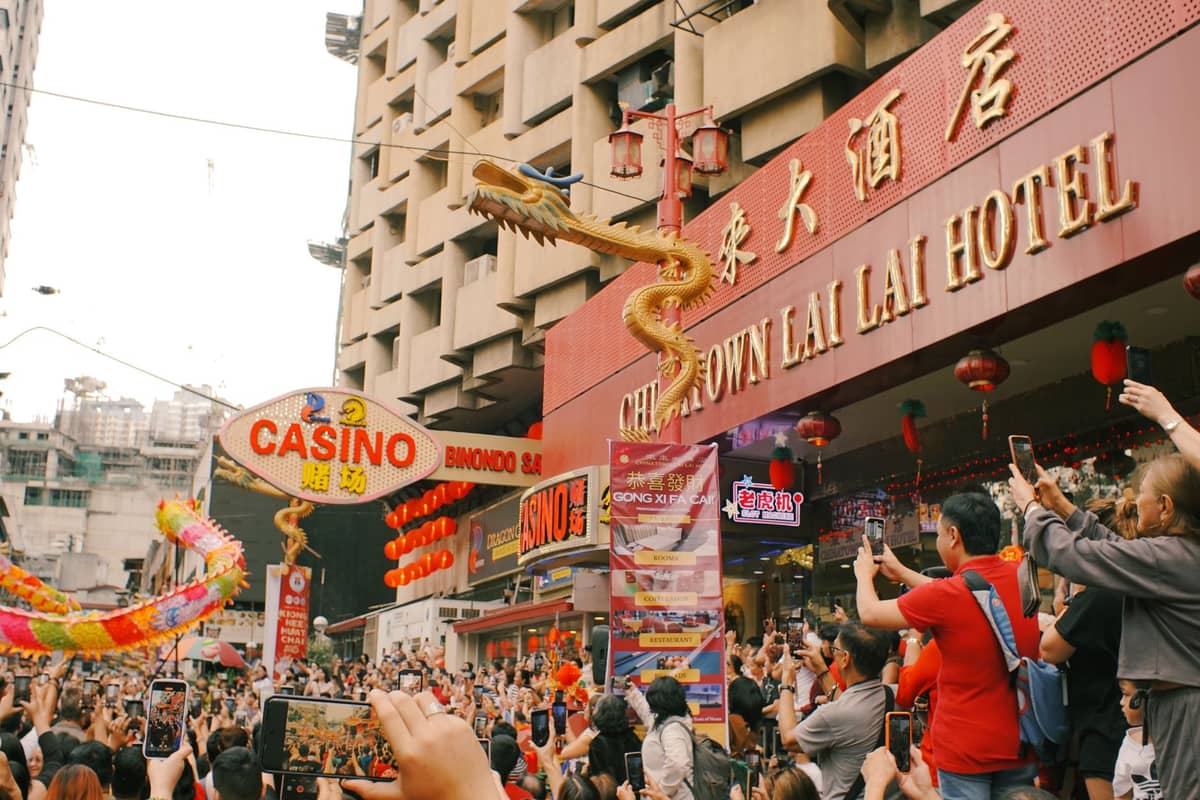 Menschenmassen beobachten eine lebhafte goldene Drachenparade vor dem imposanten Schriftzug eines Hotels und Casinos in Macau während der chinesischen Neujahrsfeierlichkeiten.