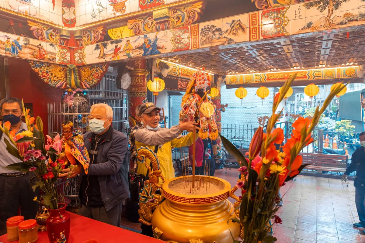 Menschen, die Weihrauch opfern und Rituale in einem reich verzierten chinesischen Tempel während einer Festzeit durchführen