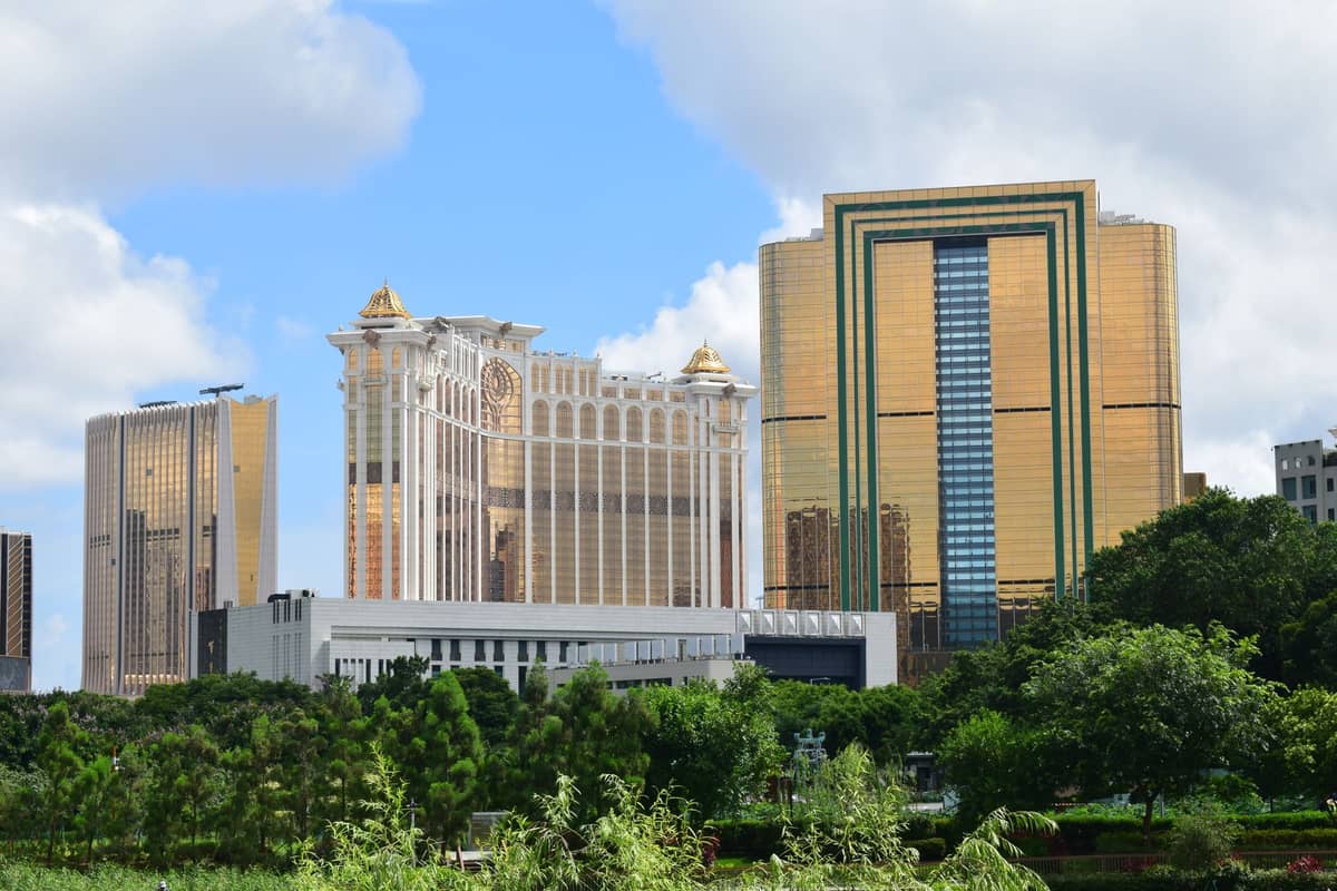 Außenansicht der Casinoresorts in Macau mit gold-weißen Türmen unter blauem Himmel, umgeben von Grünflächen