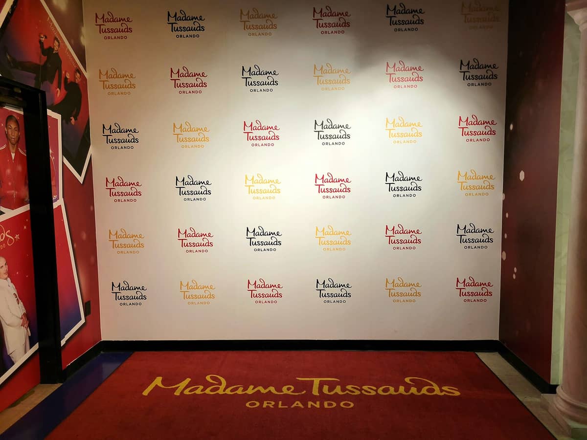Interior backdrop wall and carpet featuring Madame Tussauds Orlando logo, inside the wax museum at ICON Park.