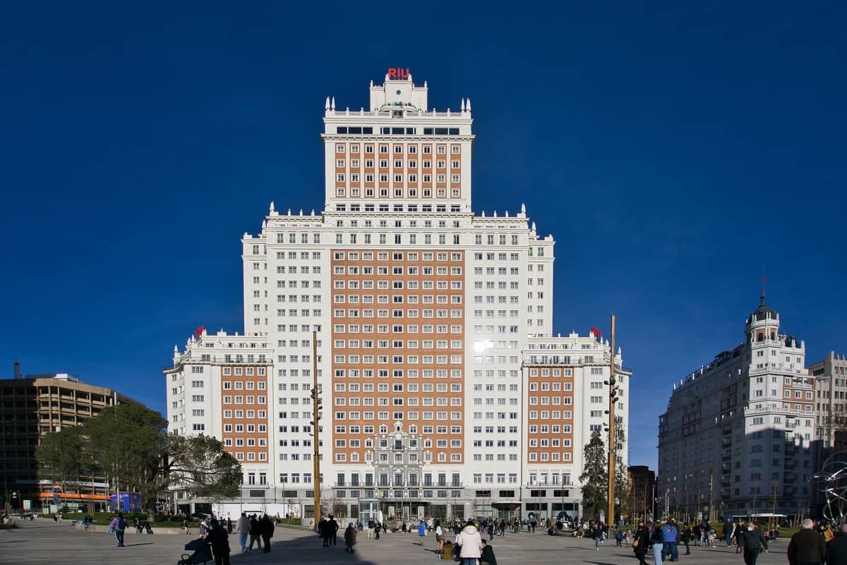 Frontansicht des Edificio España in Madrid, ein monumentaler Nachkriegs-Wolkenkratzer mit einer gestuften Silhouette vor einem klaren blauen Himmel.