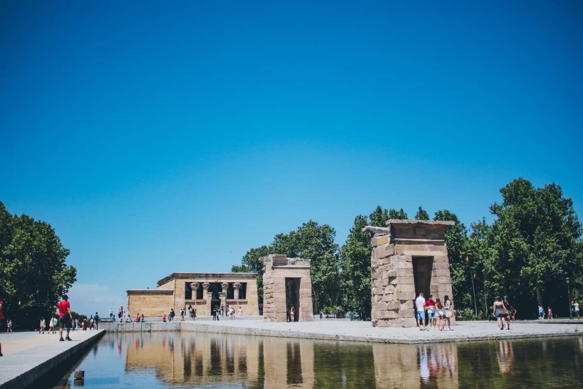 Der Templo de Debod in Madrid mit Besuchern und Spiegelung im Wasser unter einem klaren blauen Himmel