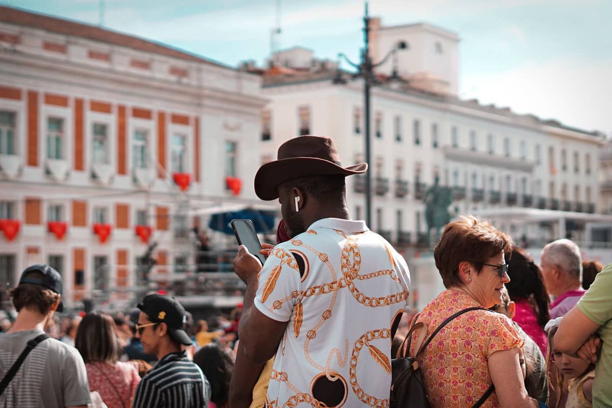 Folla di persone alla Puerta del Sol di Madrid, con edifici caratteristici sullo sfondo e turisti che si mescolano, mostrando una vivace scena cittadina.