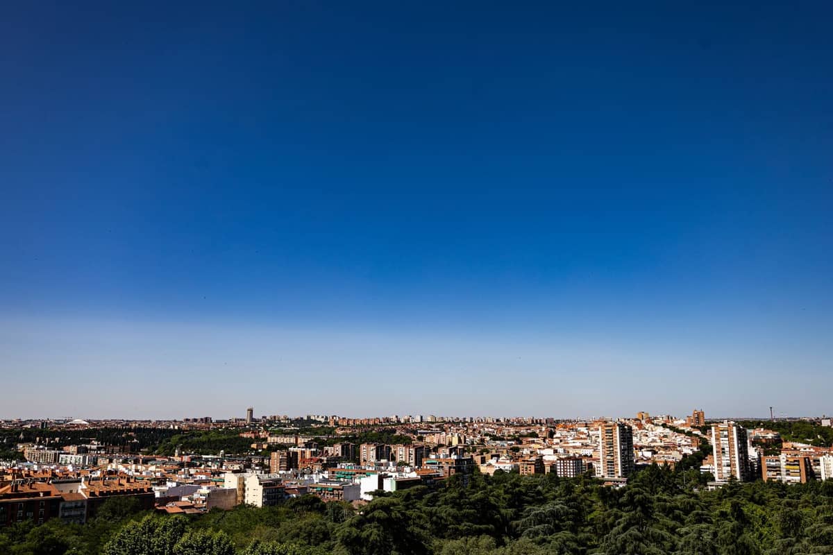 Ampio panorama urbano di Madrid sotto un cielo blu intenso e senza nuvole, con edifici e intensa luce solare estiva.
