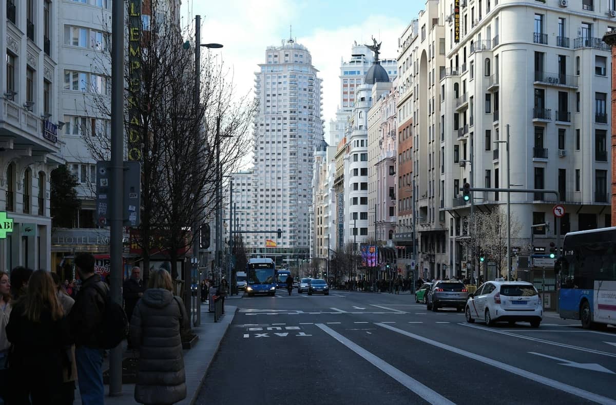 Gran Vía im Zentrum von Madrid mit Menschen in Wintermänteln und kahlen Bäumen entlang der Allee unter einem klaren Himmel