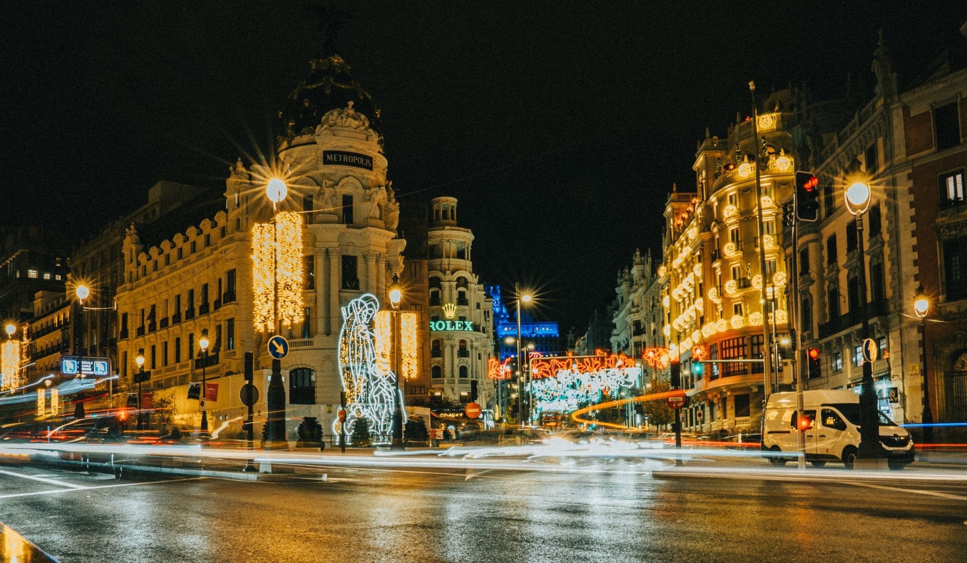 A Gran Via de Madri à noite no inverno, com luzes festivas de Natal e prédios iluminados criando uma atmosfera vibrante de fim de ano.