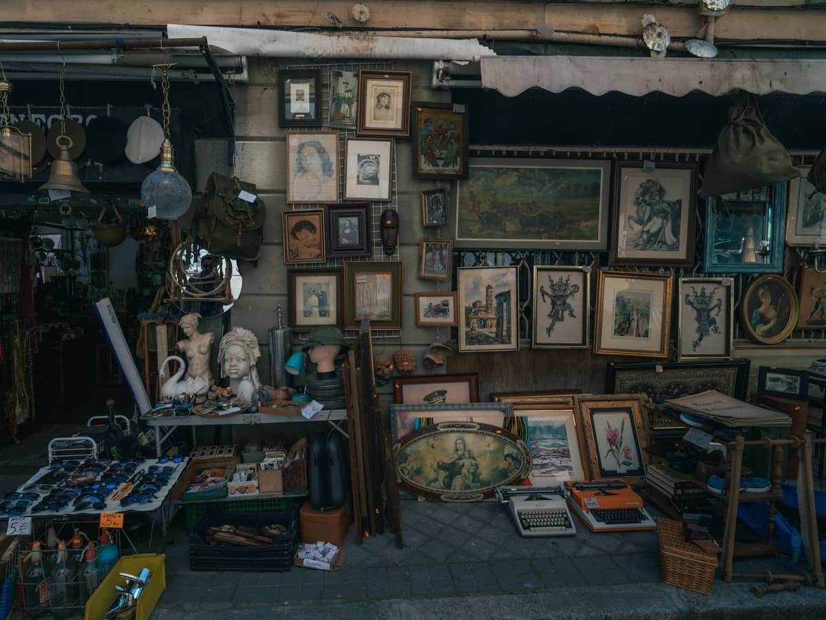 Flohmarktstand im Freien mit Vintage-Gemälden, Skulpturen und verschiedenen Antiquitäten auf einer Straße in Madrid.