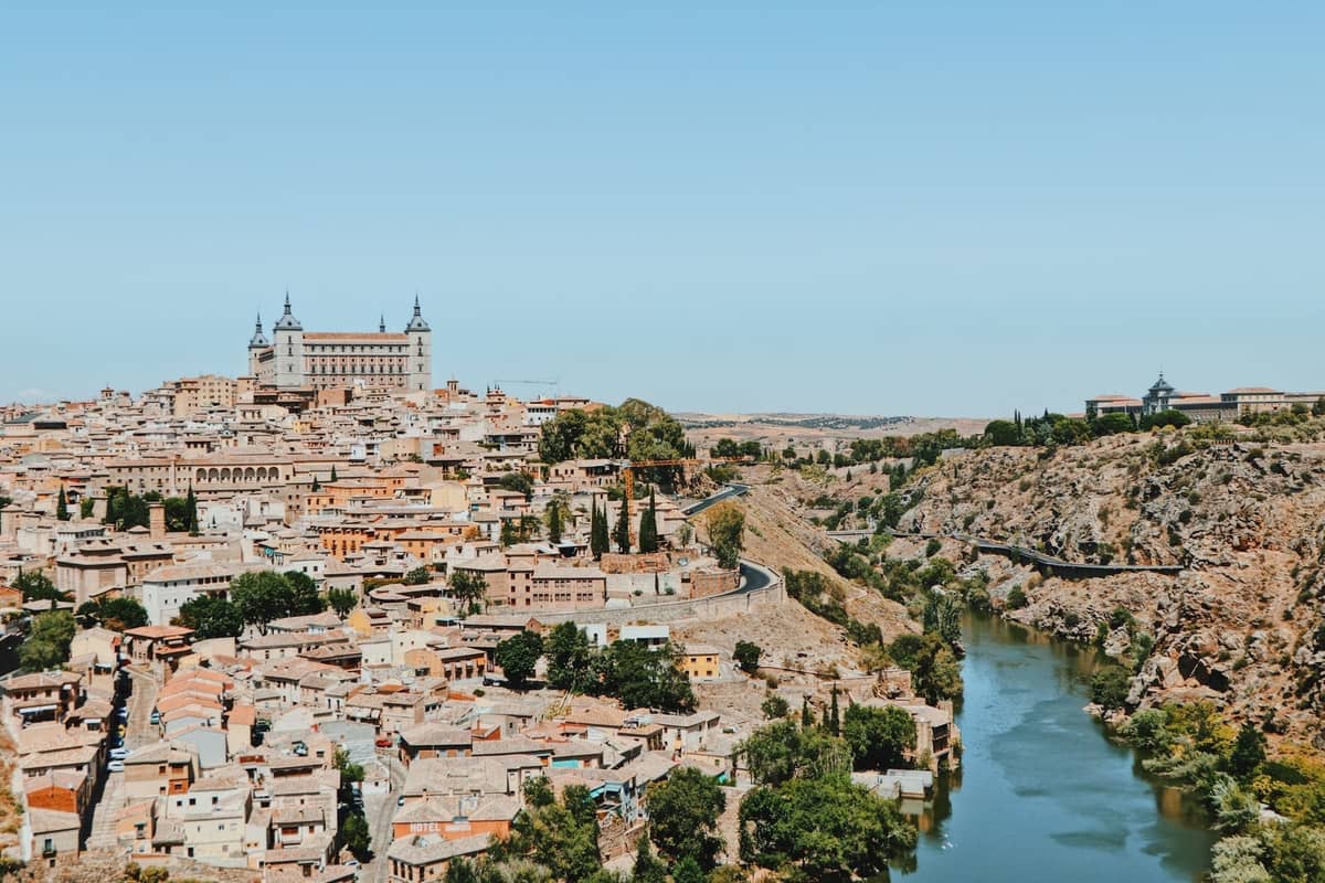 Wide panoramic view of Toledo’s old town, river and Alcázar under a clear blue sky, showing why it’s a classic Madrid day trip.