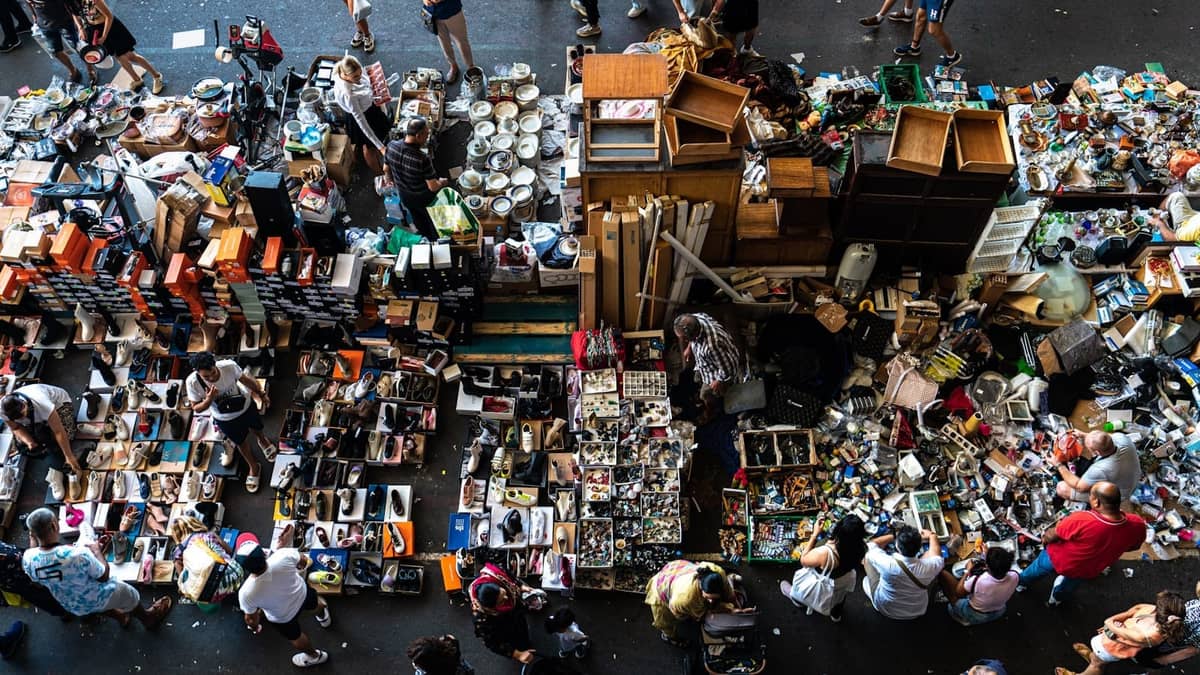 Vista aérea de un concurrido mercado de pulgas con puestos que venden antigüedades variadas, coleccionables y artículos de segunda mano, rodeado de compradores en Madrid.
