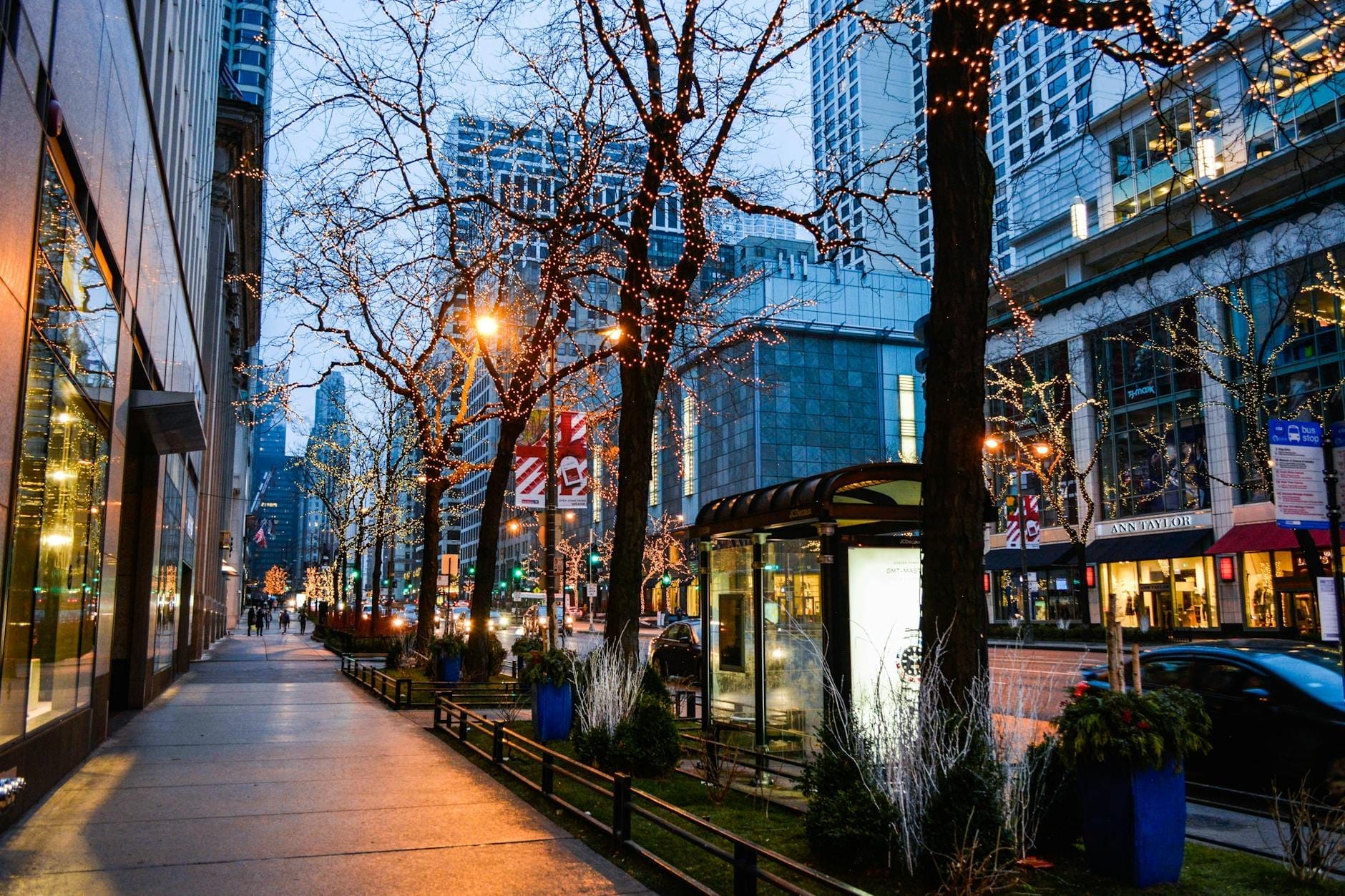 วิวถนน Magnificent Mile ยามค่ำในชิคาโก ไฟระยิบระยับประดับต้นไม้ หน้าร้านหรู และตึกระฟ้าริมทางเดินพลุกพล่าน