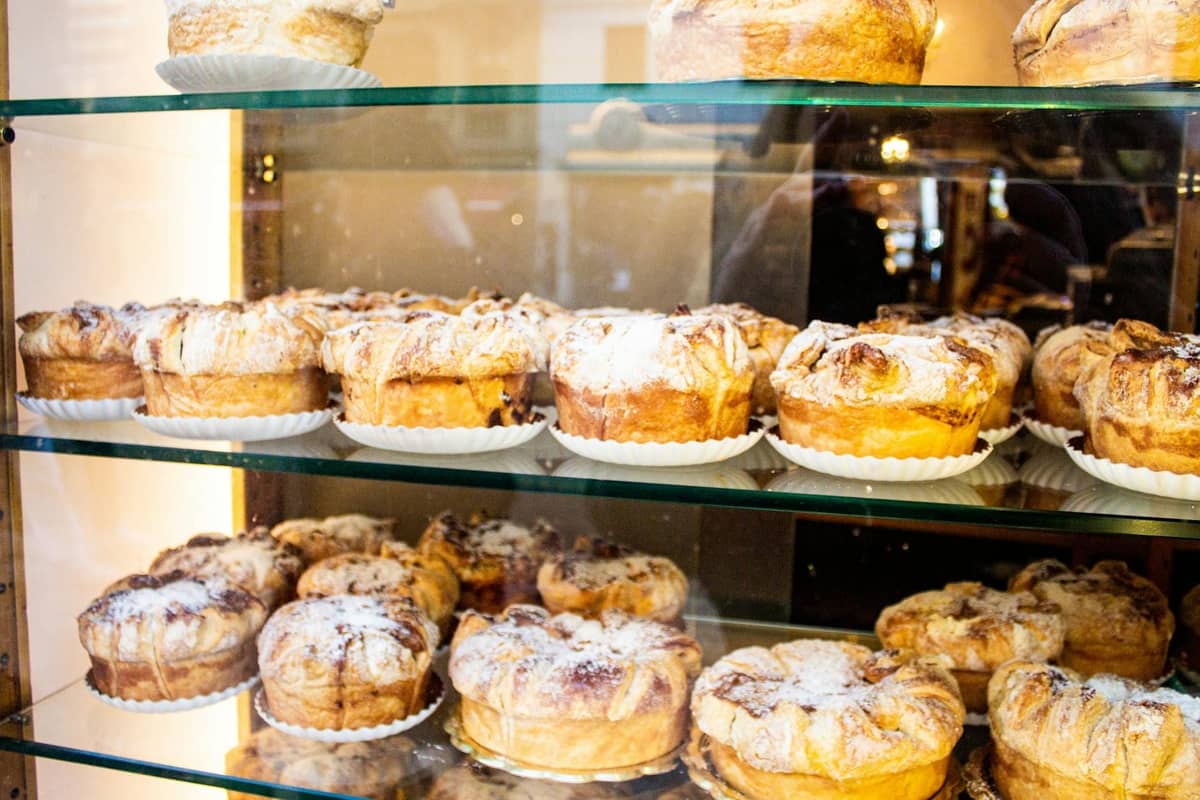 Gläserne Vitrine gefüllt mit runden Gebäckstücken, die mit Puderzucker bestäubt sind und an traditionelle mallorquinische Ensaimadas in einer Bäckerei erinnern.