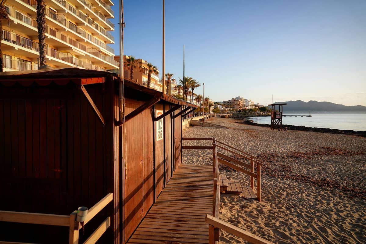 Mallorca'da apartman binaları ve bir cankurtaran kulübesiyle neredeyse boş bir plajın sabah erken saatlerdeki görünümü, sezon dışı huzuru çağrıştırıyor.