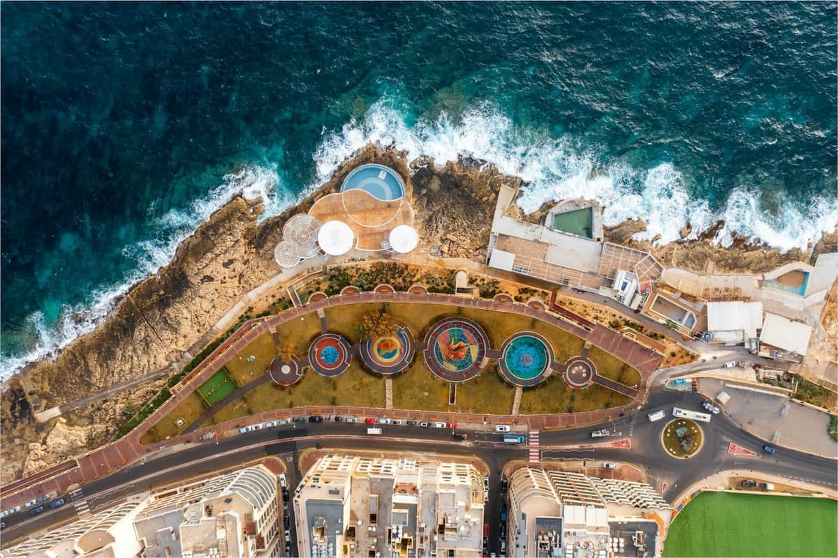 Vista aerea della costa rocciosa con piscine e lettini del beach club sul mare a Malta