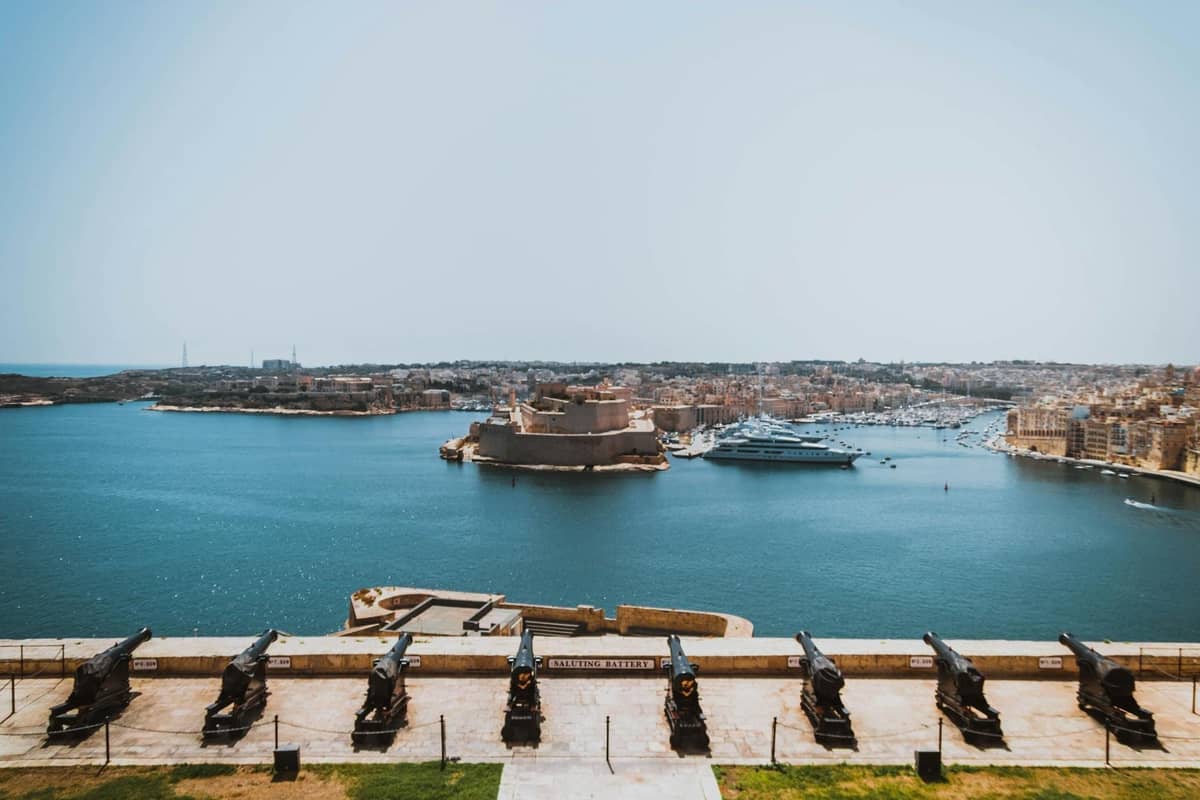 Panoramiczny widok na port Valletty z historycznymi fortyfikacjami, bastionami i armatami Saluting Battery z widokiem na wodę i Trzy Miasta na Malcie.