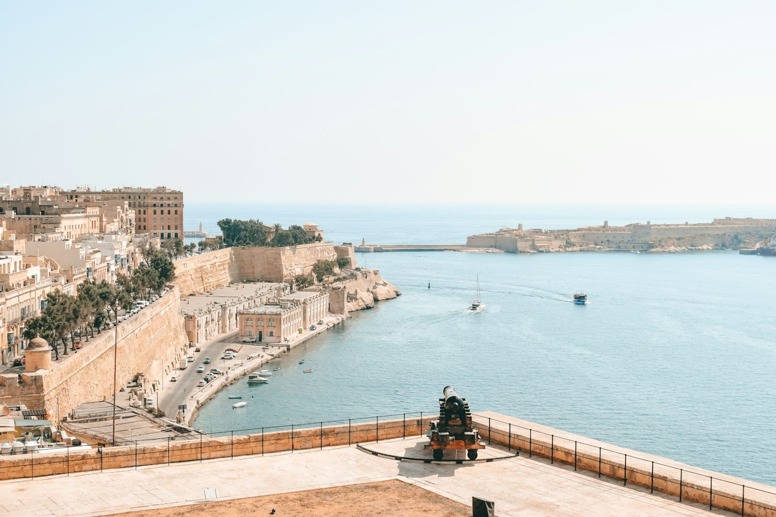 Vista ampla das icônicas fortificações de calcário e do porto de Valletta sob um céu limpo, com barcos no Mediterrâneo — imagem perfeita para introduzir um roteiro de viagem a Malta.
