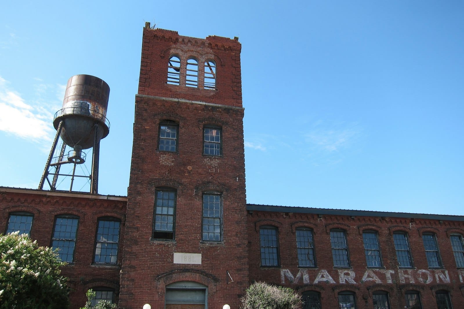Histórica fábrica de ladrillo rojo de Marathon Village en Nashville con ventanas altas, torre de agua envejecida y cielo azul despejado al fondo.