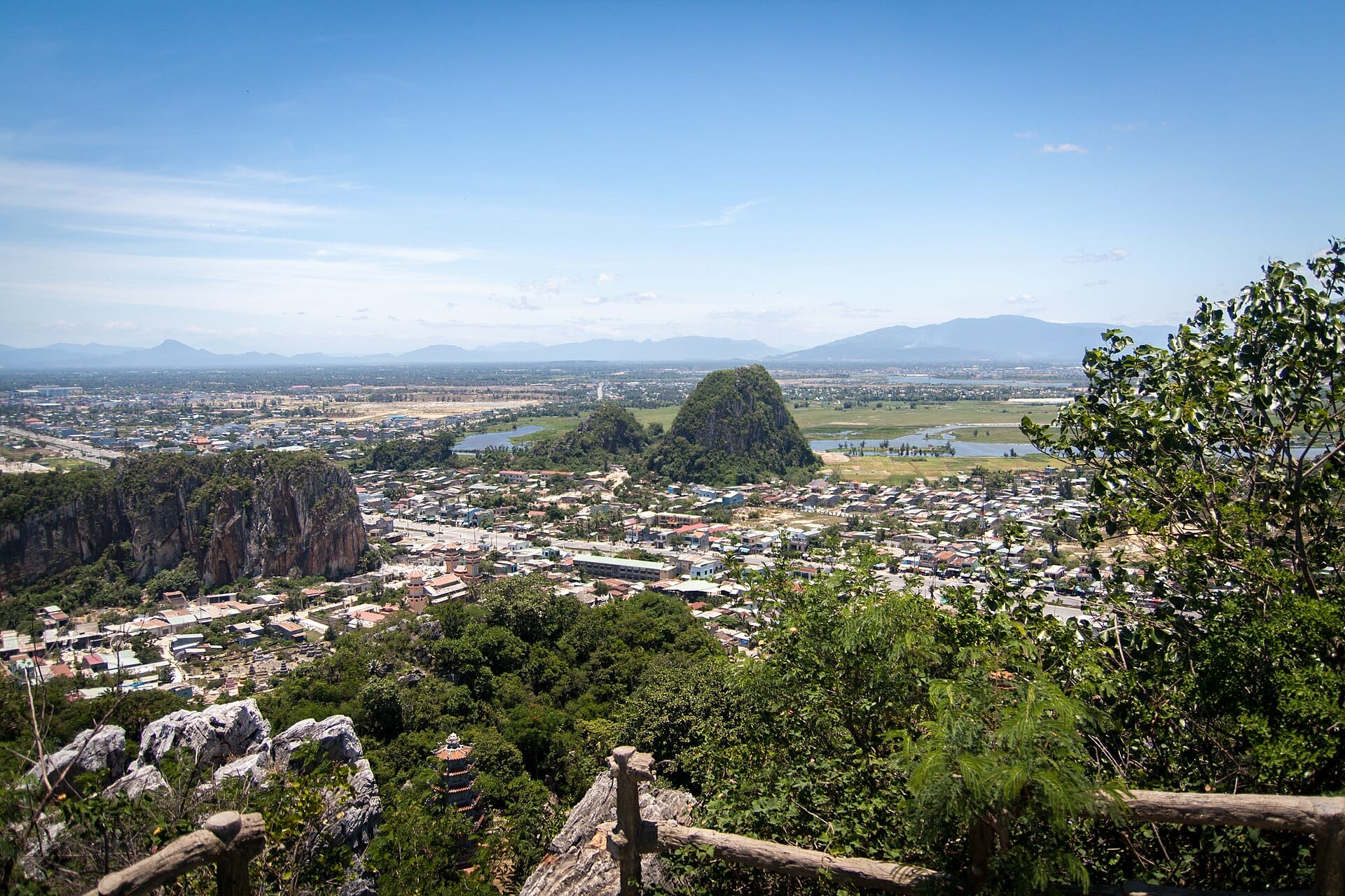 วิวพาโนรามาของภูเขาหินอ่อน (Ngu Hanh Son) โผล่ขึ้นมาท่ามกลางบ้านเรือน ล้อมรอบด้วยเนินเขาและโขดหินท่ามกลางท้องฟ้าสีครามสดใส