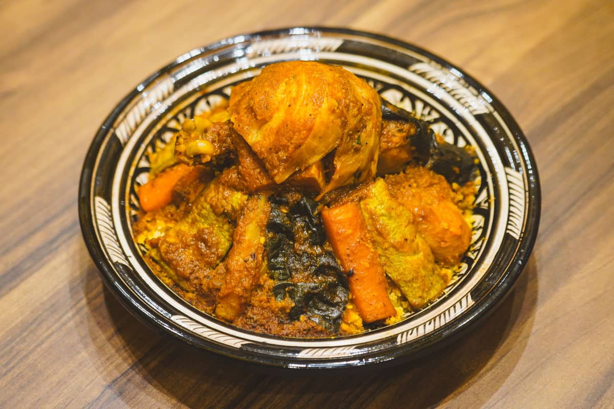 ทาจีนโมร็อกโกสูตรดั้งเดิมในชามเซรามิคลวดลายสวย ใส่ไก่ ผัก และเครื่องเทศ วางบนโต๊ะไม้