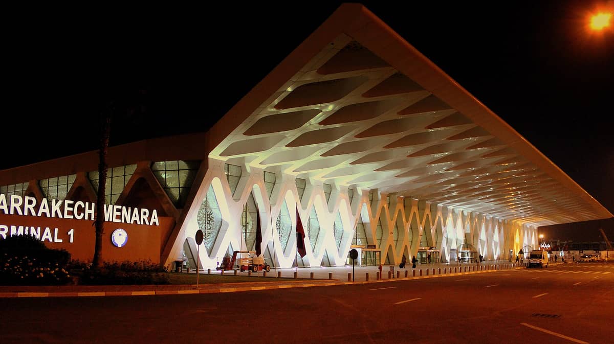 วิวกลางคืนของอาคารผู้โดยสาร 1 สนามบิน Marrakech Menara ที่ทันสมัยและสว่างไสวพร้อมลวดลายเรขาคณิตและป้ายสัญลักษณ์