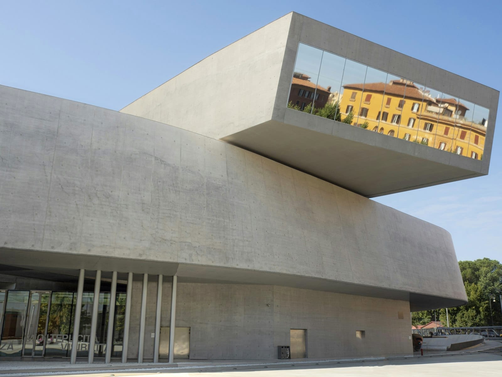 Exterior of the MAXXI National Museum, featuring striking modern concrete architecture and reflective windows under a clear blue sky.