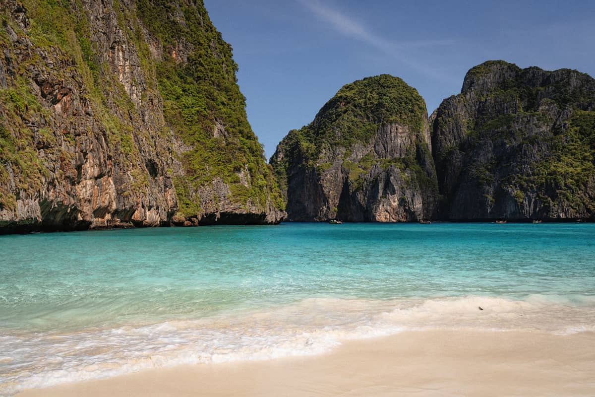 ภาพพาโนราม่าชายหาดทรายขาวของอ่าวมาหยา น้ำทะเลฟ้าใส รายล้อมด้วยหน้าผาหินปูนสูง ตัดกับท้องฟ้าสดใสในมุมที่ทุกคนคาดหวังจากสถานที่นี้