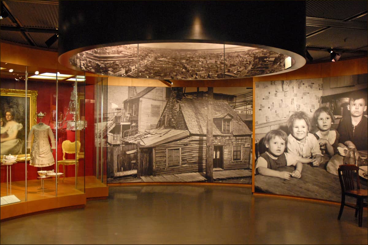 Ausstellungssaal im McCord Stewart Museum mit historischen Fotografien, Vintage-Kleidung und Artefakten zur kanadischen Sozialgeschichte.