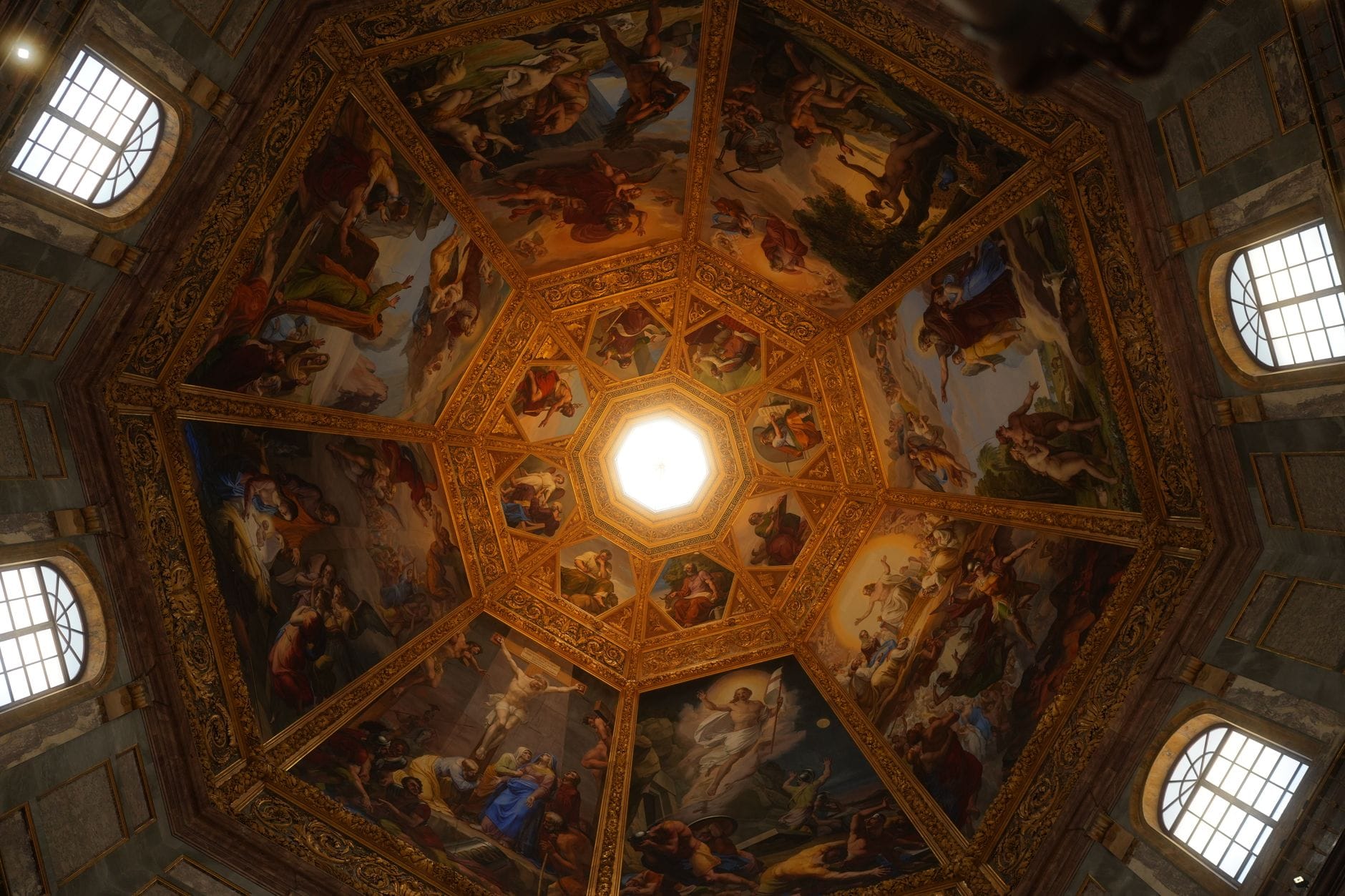 มุมมองภายในมองขึ้นไปยังโดมวาดฟรสโกและแสงสกายไลท์กลาง Chapel Medici ล้อมด้วยฉากศาสนายุคเรอเนสซองส์สีสด