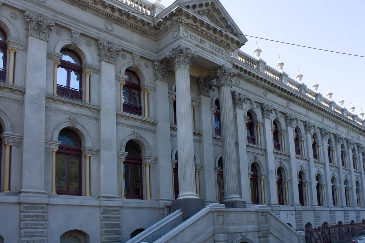 Historisches Gerichtsgebäude Melbourne mit verzierten Säulen, Bogenfenstern und einer prächtigen Steinfassade bei klarem Tageslicht.