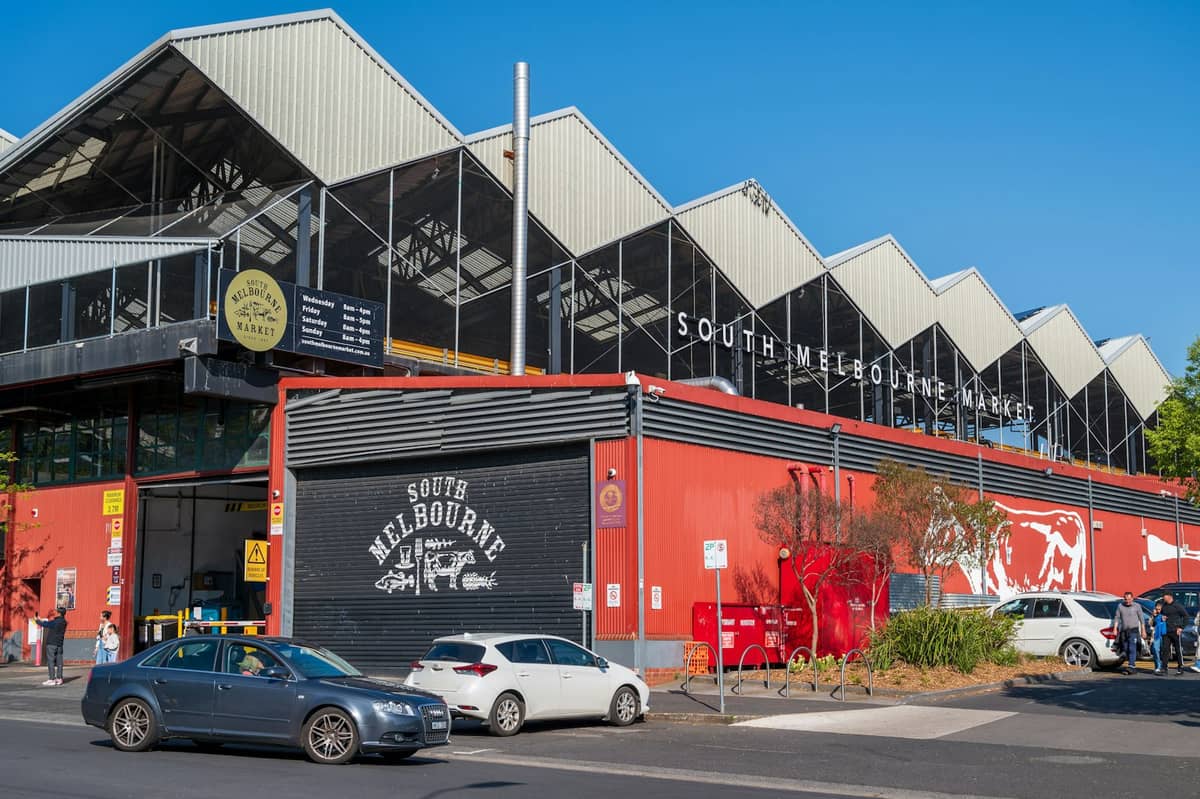 Außenansicht des South Melbourne Market-Gebäudes mit seinem markanten Sägezahndach und Beschilderung an einem sonnigen Tag.