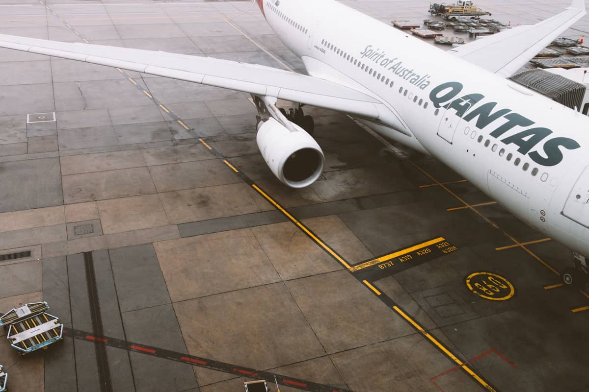 Qantas-Flugzeug auf dem Rollfeld eines Flughafens geparkt, von oben aufgenommen mit sichtbarem Teil des Flügels und des Triebwerks.