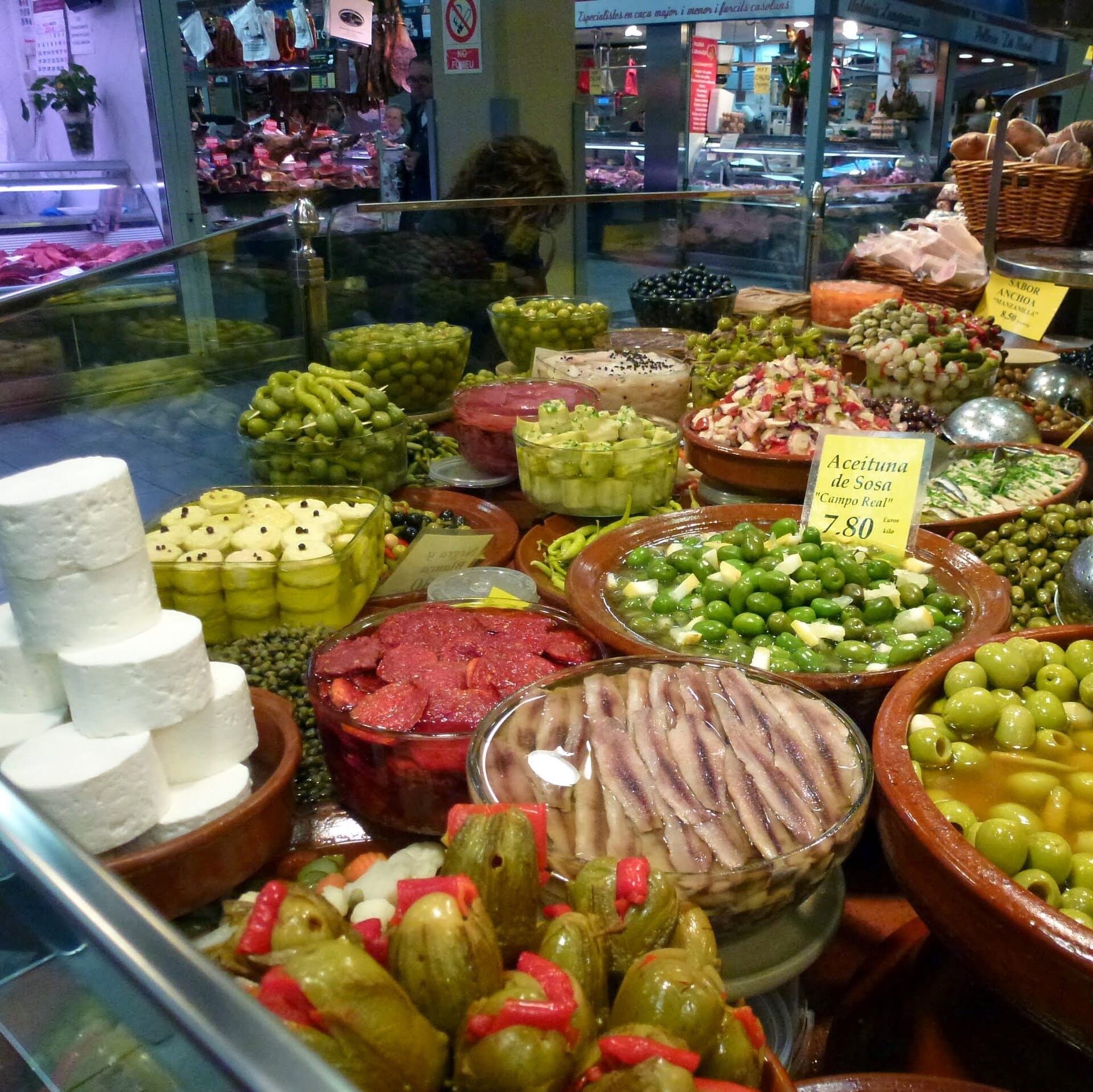 Colorato assortimento di olive, formaggi e verdure in salamoia in mostra presso un vivace banco all'interno del Mercat de l'Olivar a Palma.