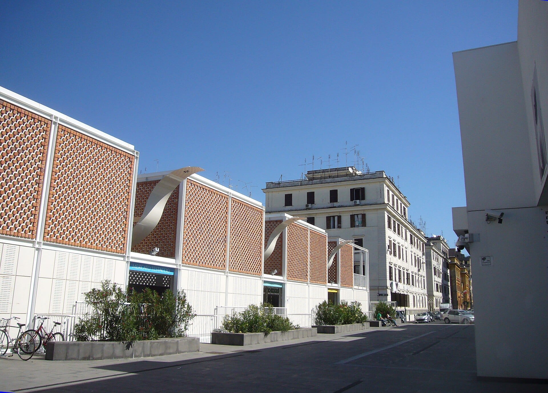 Exterior of Nuovo Mercato di Testaccio in Rome featuring modern brick lattice architecture under a clear blue sky and surrounding city buildings.
