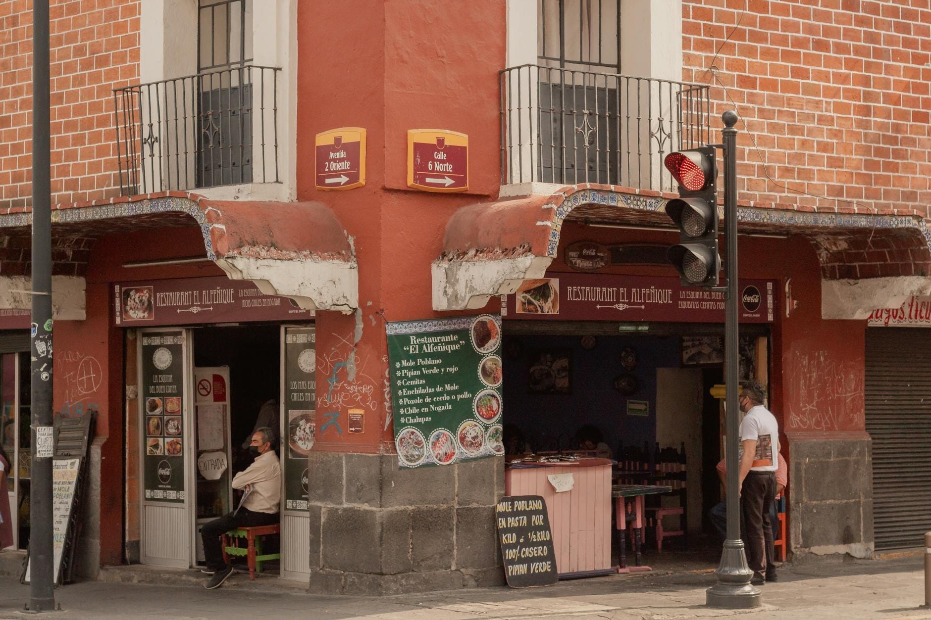 Pessoas sentadas e relaxando em um restaurante de esquina sombreado na Cidade do México durante o dia.