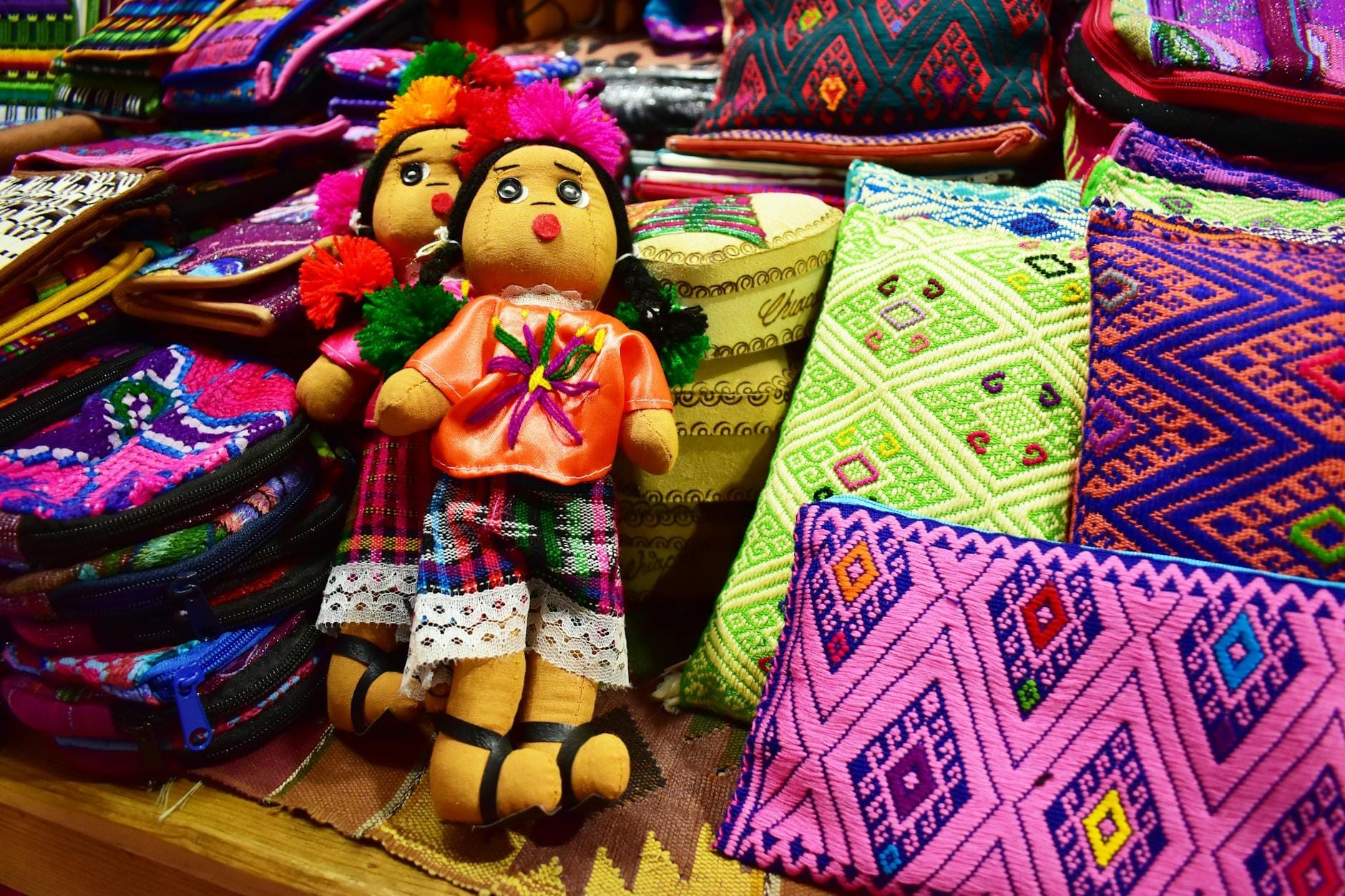 Bonecas mexicanas artesanais coloridas e têxteis em exibição em uma barraca de mercado de artesanato.