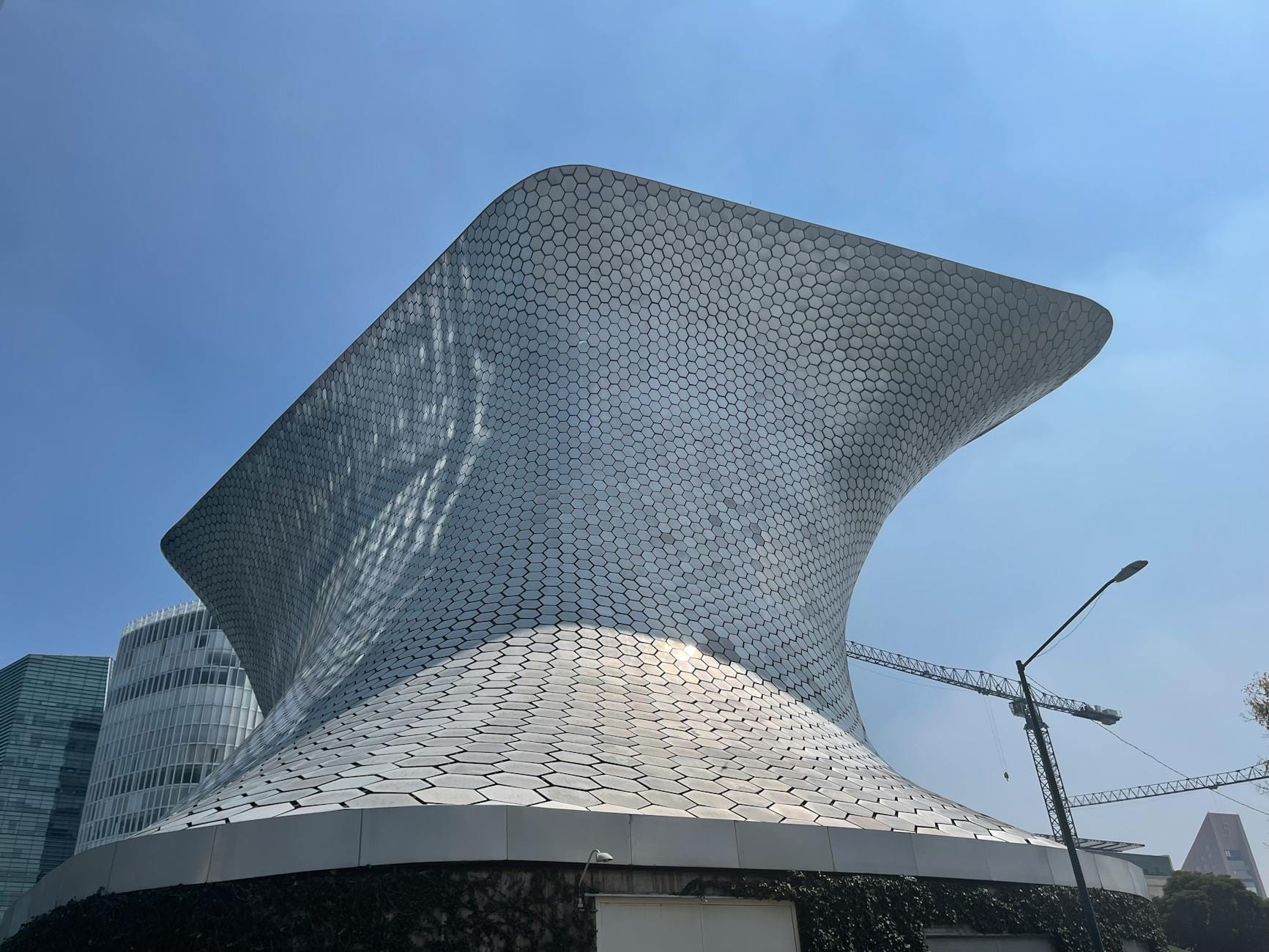 Edifício moderno com azulejos hexagonais prateados do Museo Soumaya em Polanco com céu azul e alguns arranha-céus próximos.