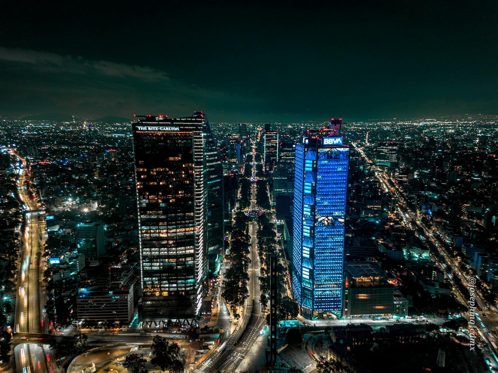 Vista aérea noturna da Cidade do México com arranha-céus iluminados, ruas movimentadas e luzes da cidade se estendendo ao horizonte, capturando a atmosfera vibrante da vida noturna.