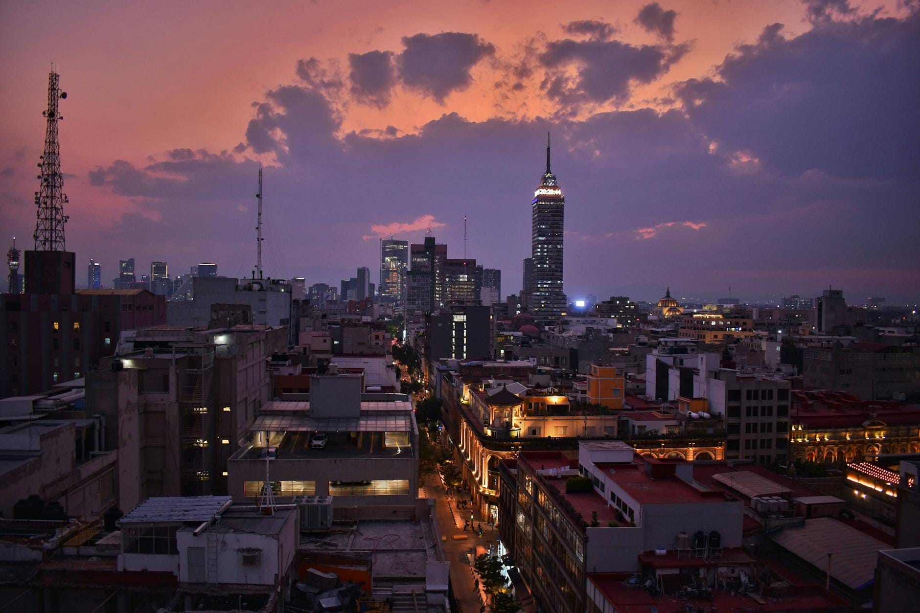 Horizonte da Cidade do México ao entardecer com um céu dramático e a Torre Latinoamericana, mostrando as luzes da cidade se acendendo com a chegada da noite.