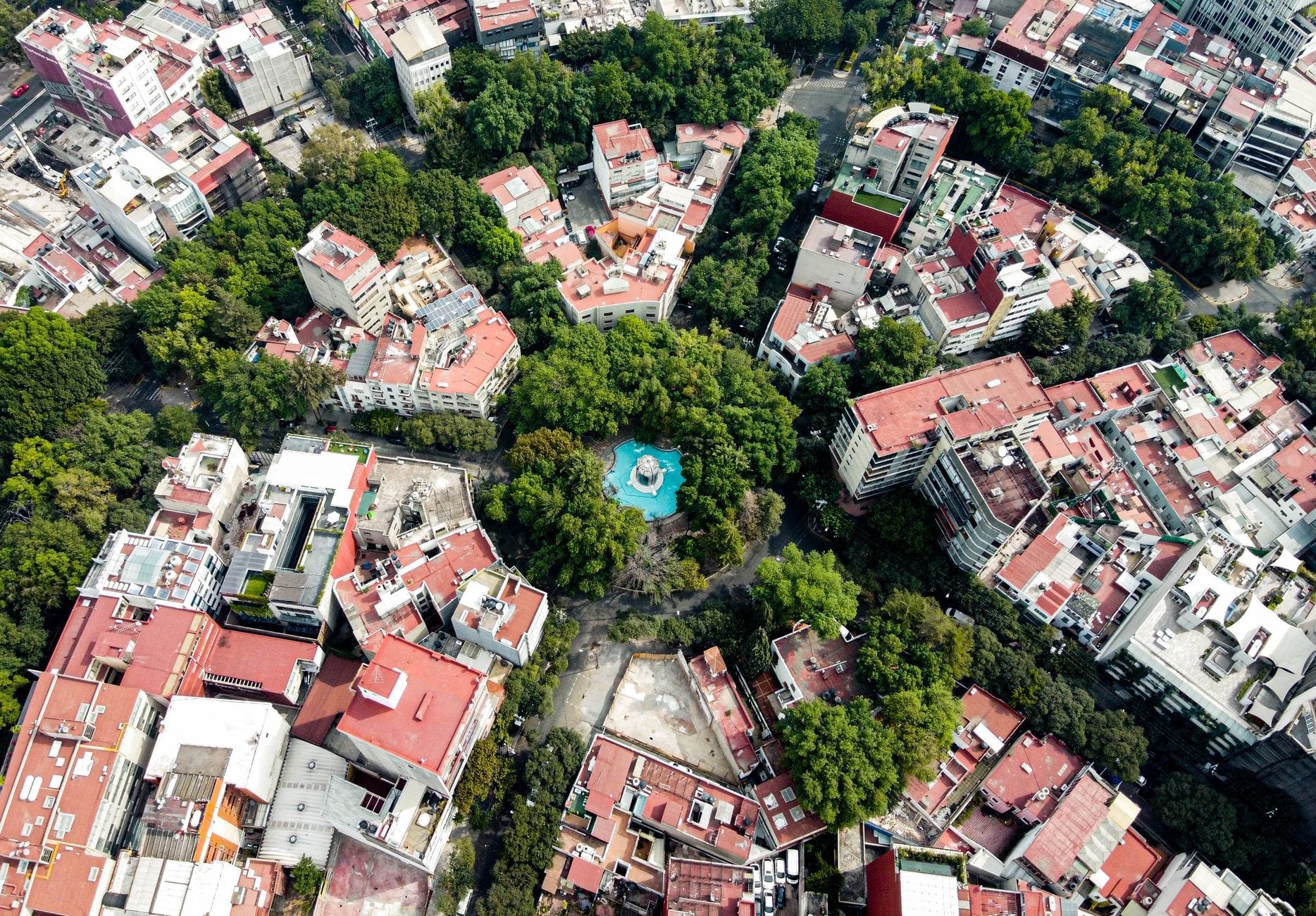 Vista aérea da Cidade do México mostrando bairros organizados em torno de uma praça circular arborizada com edifícios e ruas variados.
