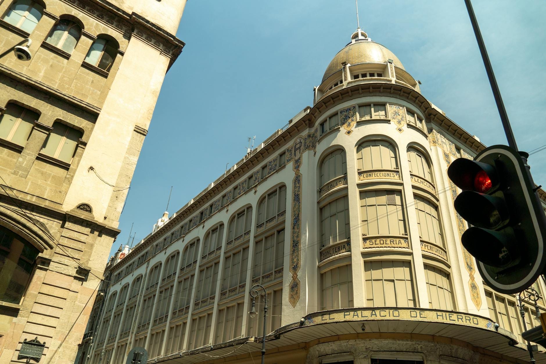 Elegante edifício histórico da loja de departamentos El Palacio de Hierro na Cidade do México, visto ao nível da rua sob um céu azul.