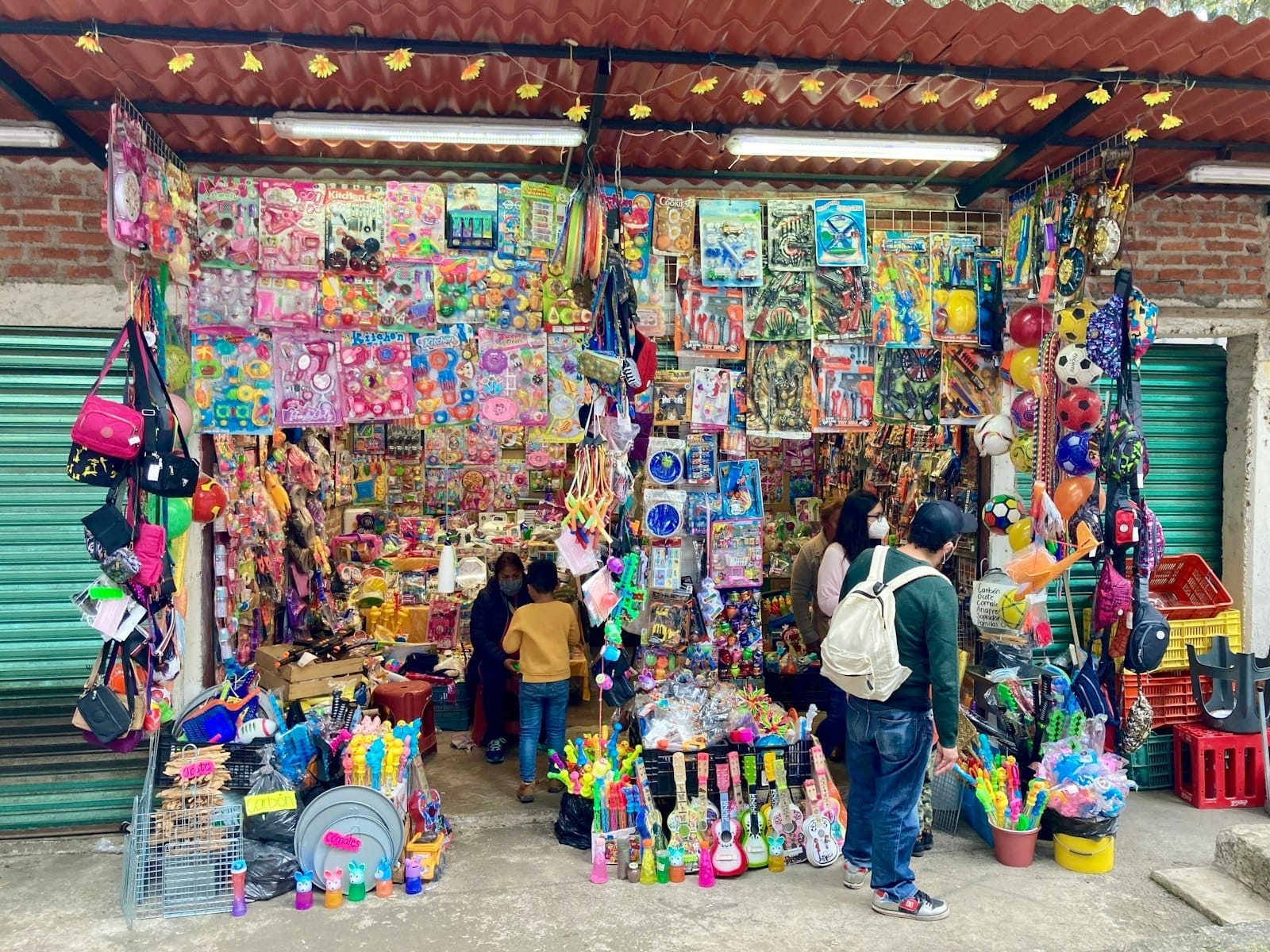 Uma barraca de mercado de rua colorida repleta de brinquedos, jogos e crianças explorando ao lado de adultos na Cidade do México.