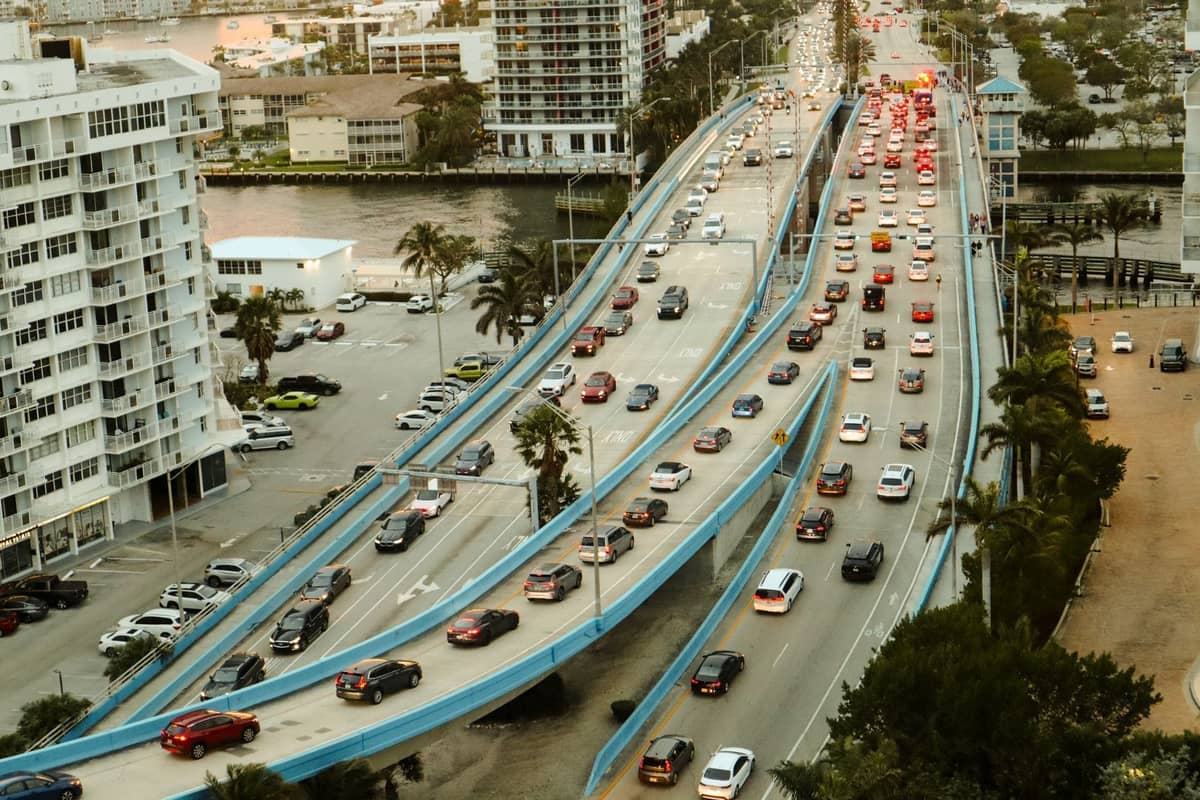Aerial view of a busy Miami bridge with heavy traffic, high-rise hotels, and apartments beside Intracoastal waterways.