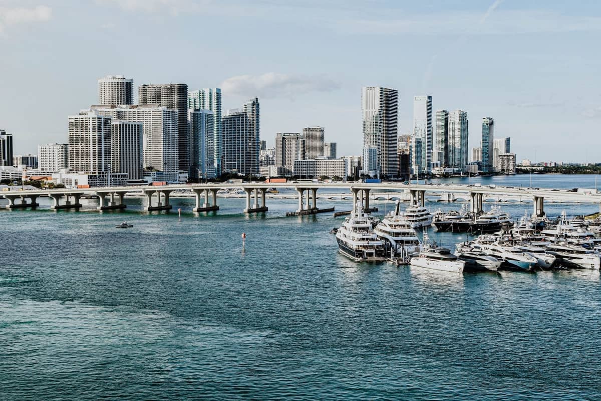 Luxury yachts docked in Miami marina with downtown skyscrapers in the background on a sunny day.