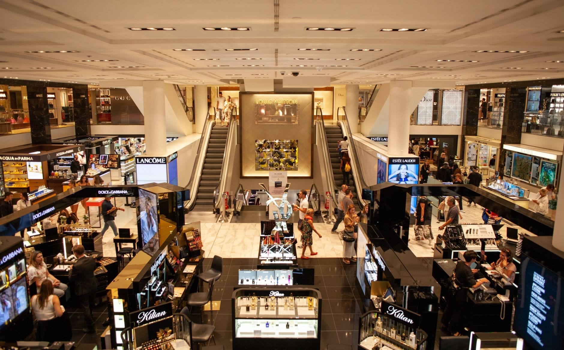 Interior amplo de um shopping sofisticado em Miami, com consumidores circulando entre vitrines de marcas de luxo e iluminação vibrante.